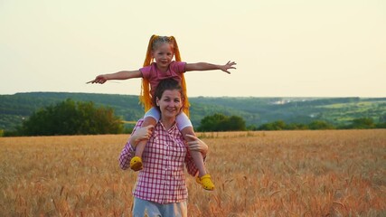 Mom and daughter on shoulders have fun in field. Family and nature in summer at sunset. Little girl and woman on vacation. Smile be happy. Friendship of two daughters can fly. Farmers play in field.