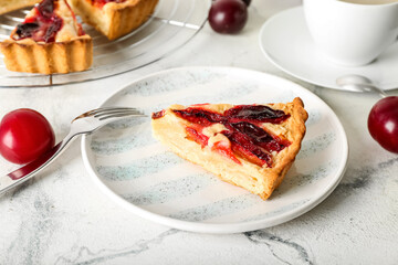 Plate with piece of tasty plum pie on light background, closeup