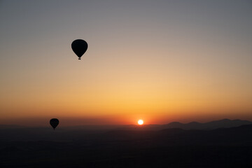 hot air balloon silhouettes with sun rising over the mountains