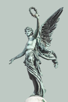 Column statue of renaissance era angel with wings and flowers wreath in Vienna, at solid background, Austria, details, closeup. Concept of historical and religious heritage.