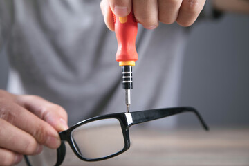 Optical technician repairing eyeglasses with screwdriver.