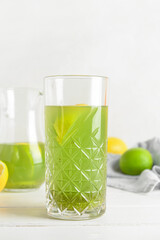 Glass with tasty lemonade on light wooden table