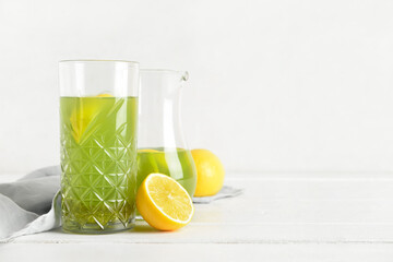 Glass with tasty lemonade on light wooden table