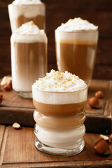 Glasses of tasty latte with nuts on wooden background