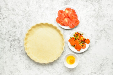 Raw dough and fresh vegetables for preparing pot pie on light background