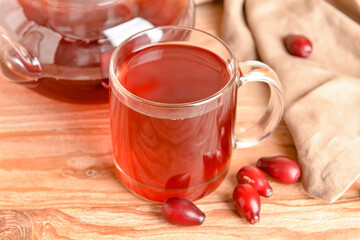 Glass cup of fresh dogwood drink on wooden table, closeup