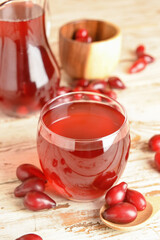 Glass of delicious dogwood drink on light wooden background