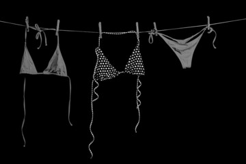 Swimsuit. Female swimwear hanging on rope isolated on black background. Bikini swimsuit dries on a rope.