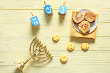 Fototapeta na wymiar Tasty cookies and potato pancakes for Hanukkah celebration with dreidels and menorah on color wooden background