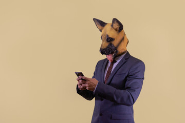 Empresario con mascara de perro mandando un mensaje de texto, en fondo marrón latte, con espacio para texto.
