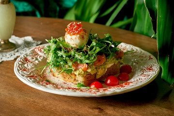 Appetizing toast sandwich: bread, avocado, cream cheese, cherry tomatoes, salmon, arugula, microgreen, egg, red caviar.