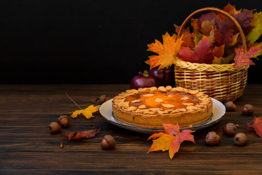 Autumn background with pumpkin cake, maple leaves, aples and acorns. Copy space