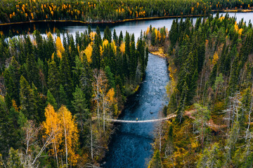 Aerial view of fall forest and blue river with bridge in Finland.
