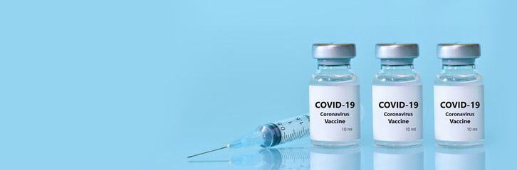 Three vials with a vaccine, a syringe on a blue background.The concept of medicine, healthcare and science.Coronavirus vaccine.Copy space for text..Banner