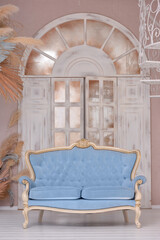 Vintage blue sofa on a background of beige wooden doors in the form of an arch