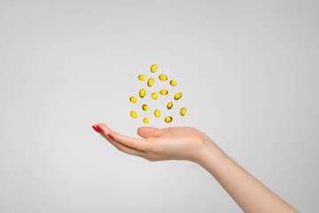 Yellow fish oil pills hover over hand