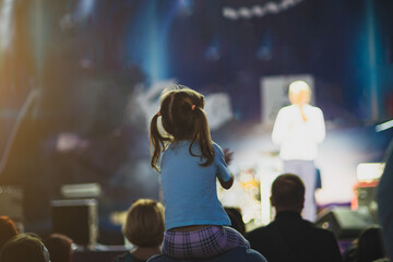 Girl sitting on daddy's shoulders at a street concert