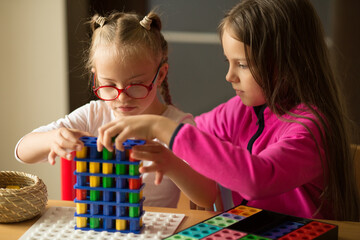 A girl with Down syndrome plays a board game with her sister
