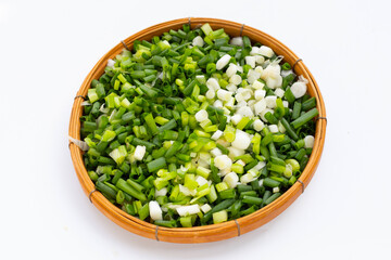 Chopped spring onions in bamboo basket on white background