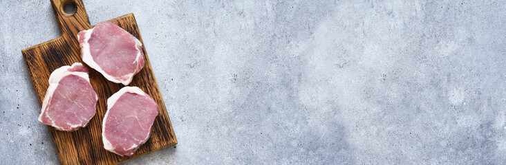 Raw pork steaks on a wooden board top view.