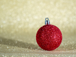 Red Christmas ball on a background of golden glitter