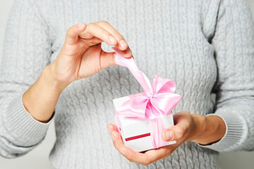 Female hands holding small gift box with ribbon on white background