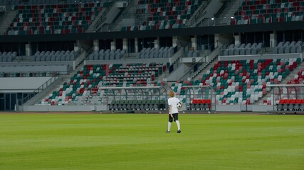 Obraz premium WIDE Caucasian pre teen kid boy entering the field of huge soccer stadium, holding a ball, dreaming of becoming professional player, soccer star