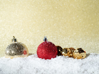 Christmas balls in the snow on a background of golden glitter.