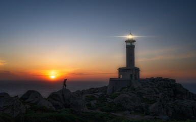 lighthouse at sunset with a man taking care of the next step