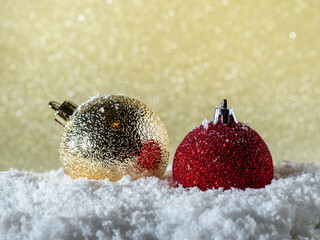 Christmas balls in the snow on a background of golden glitter.