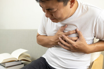 Asian middle-aged man touching his chest,suffocation and chest pain and tightness,sick male patient...
