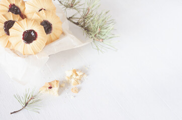 Sweet traditional christmas crumbly biscuits with jam on white wood table with green pine branches, copy space, top view.