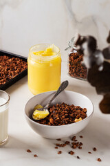 Homemade chocolate granola with ghee and milk on a light background. Healthy breakfast