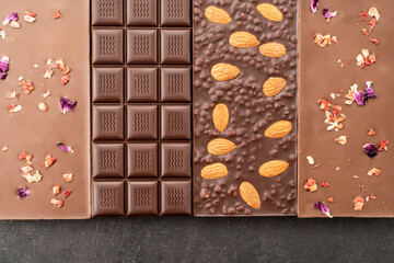 assortment chocolate bars with almonds, raspberries, handmade sweets. Composition of bars milk and dark almond chocolate, raspberries on a black background, top view. Pastry craft on the table