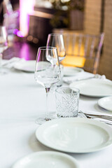 stylish empty glasses and plates at setting at elegant table for wedding reception, catering in restaurant