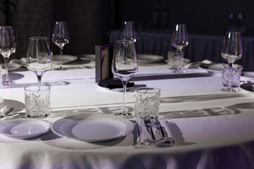 stylish empty glasses and plates at setting at elegant table for wedding reception, catering in restaurant