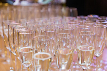 Many glasses of champagne stand on a wooden table