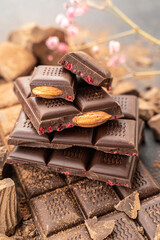Cooking chocolate bars with almonds, raspberries, handmade sweets. Composition of bars and pieces of dark almond chocolate, raspberries on a black background, top view. Pastry craft on the table