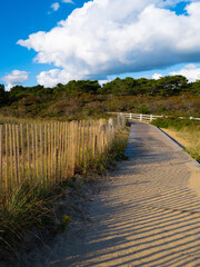 Fototapeta na wymiar Dramatic cloudscape over the boardwalks with wooden snow fence and diagonally crossing shadows