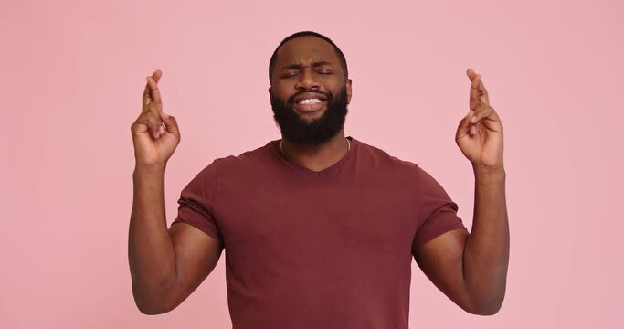 Young African american man crossing fingers isolated on pink background