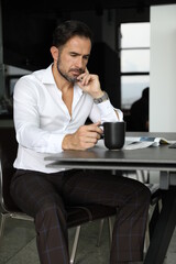 Poranna prasa i praca podczas pierwszej kawy. Przystojny mężczyzna w białej koszuli pije poranną kawę.  - obrazy, fototapety, plakaty