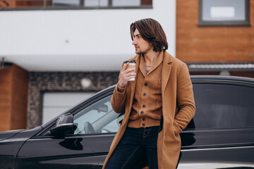 Young handsome man drinking coffee outdoors in winter time