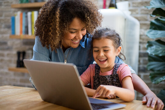 Mixed race girl using laptop for learning with mother
