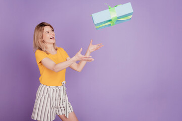 Photo of young attractive woman happy positive smile catch present gift box air fly isolated over purple color background