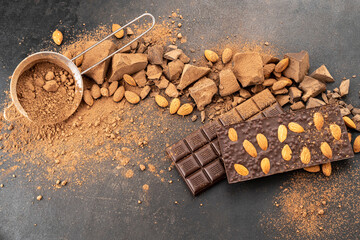 Cooking chocolate bars with almonds, handmade sweets. Composition of bars and pieces of dark almond...