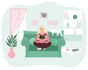 A girl is reading a book in a cozy house on the sofa with a cat.