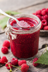 homemade raspberry jam on a wooden background with fresh raspberries, selective focus.