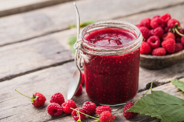 homemade raspberry jam on a wooden background with fresh raspberries, selective focus.