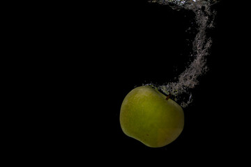 Fototapeta na wymiar Fresh fruit fall into the cold water with air bubbles as symbol for healthy vegan lifestyle in short time exposure of high speed camera