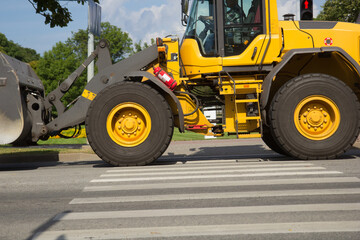 yellow excavator drive on a city street